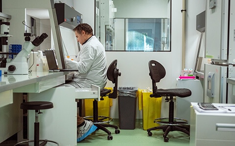 cientifique travaillant dans un laboratoire, ajustant un échantillon sous un microscope