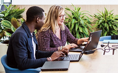 Personnes travaillant sur des ordinateurs dans un bureau moderne.