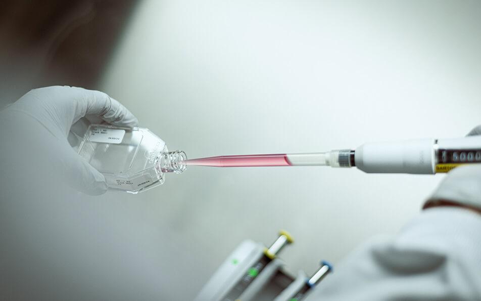 Scientifique utilisant une pipette pour transférer du liquide dans un récipient