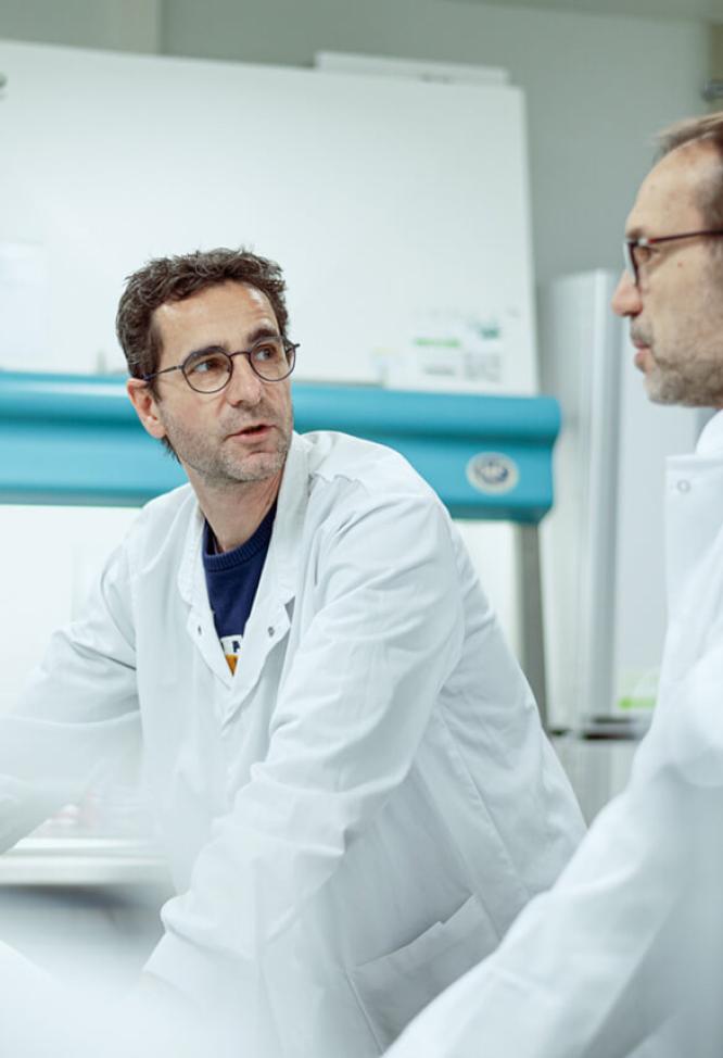 Des chercheurs en blouse blanche observent et discutent entre eux.