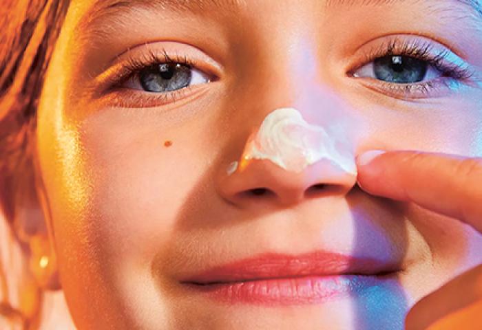 Un enfant applique une crème solaire sur son nez