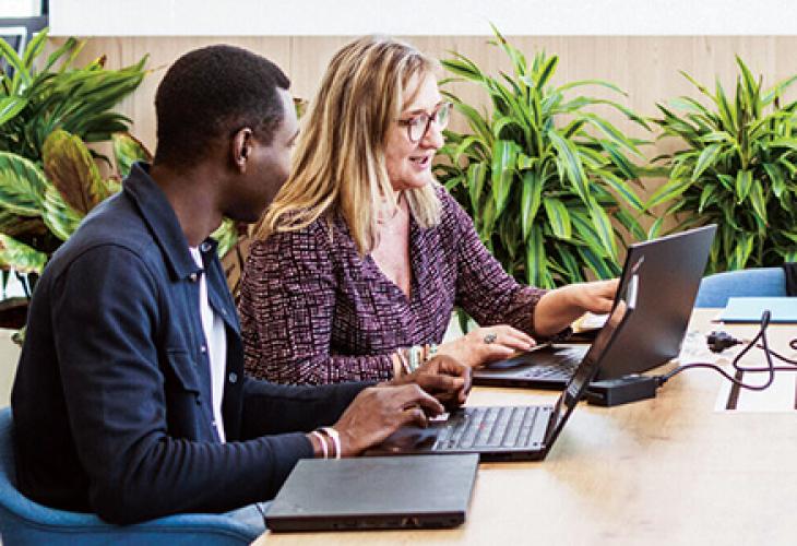 Personnes travaillant sur des ordinateurs dans un bureau moderne.